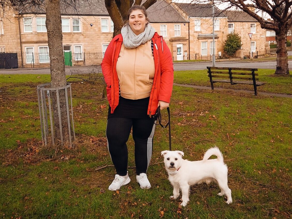 plus size woman walking a small white dog on a walk for fitness and health.